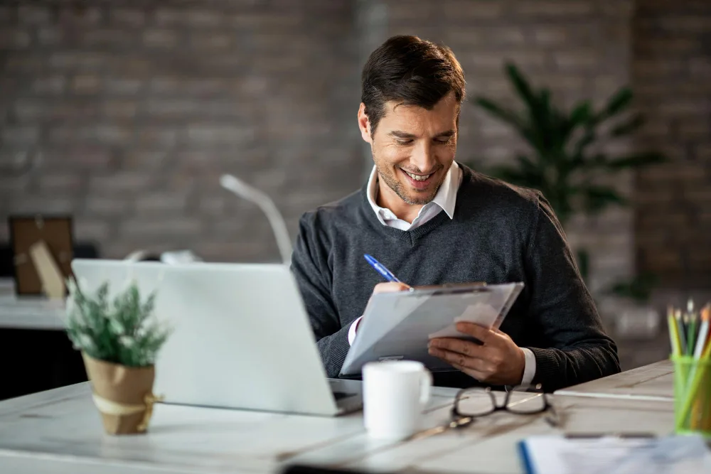 empresario sorridente escrevendo relatorio de negocios