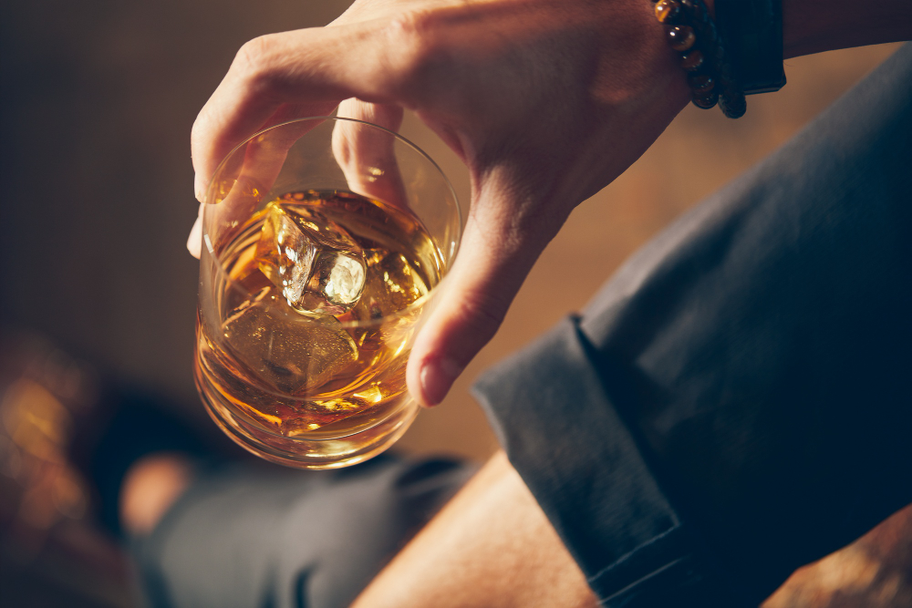 Bebidas com Whisky: Quais as melhores? 4 high angle closeup shot of a male holding a glass of whiskey